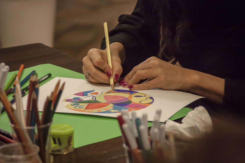 Person coloring a vibrant abstract design with colored pencils