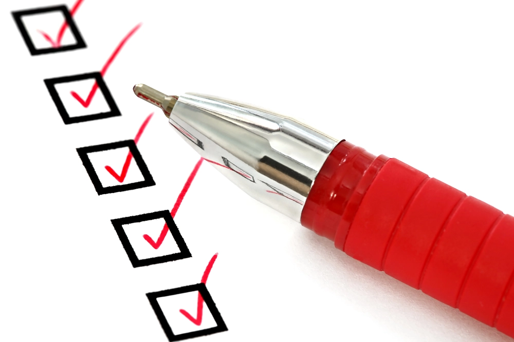 Red pen marking checkboxes on a completed checklist