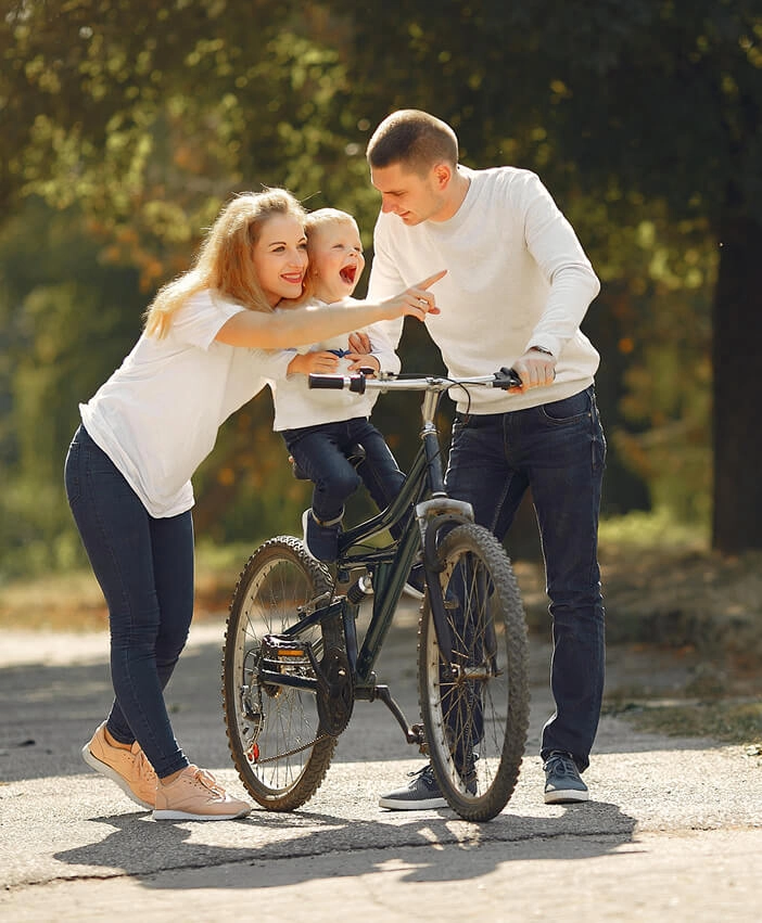 Happy family teaching their child to ride a bike outdoors, symbolizing support, growth, and togetherness