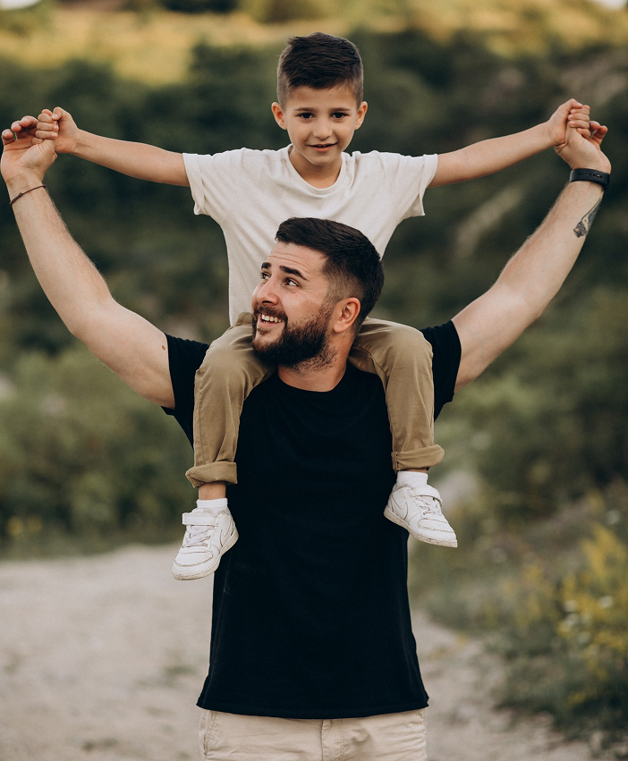Father carrying son on his shoulders outdoors, symbolizing love, connection, and positive family relationships