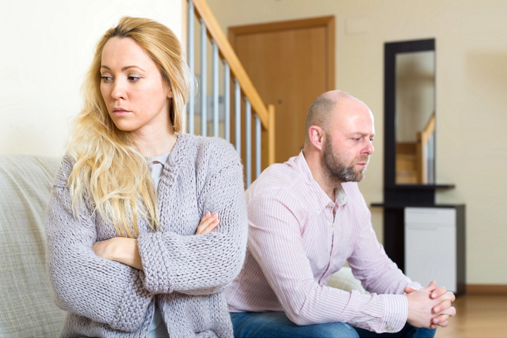 Upset couple sitting apart after an argument at home