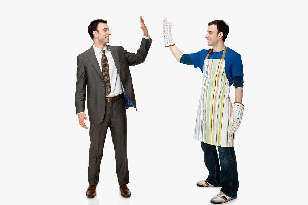 Man in business suit high-fiving man wearing apron and oven mitts, representing work-life balance and teamwork