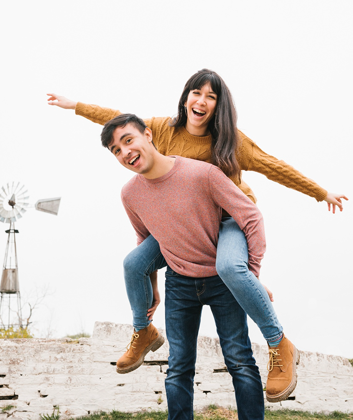 Happy couple enjoying a playful piggyback outdoors on a cloudy day