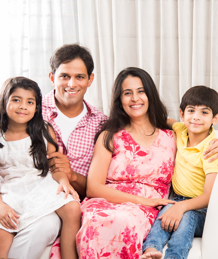 Smiling family of four sitting together on a couch at home