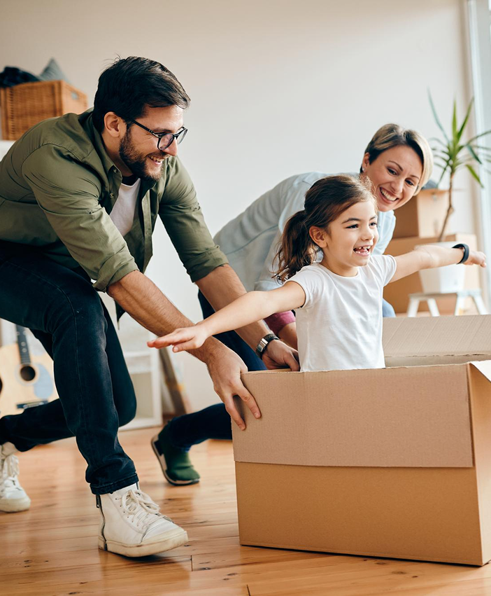 Happy parents playing with their daughter in a moving box at home