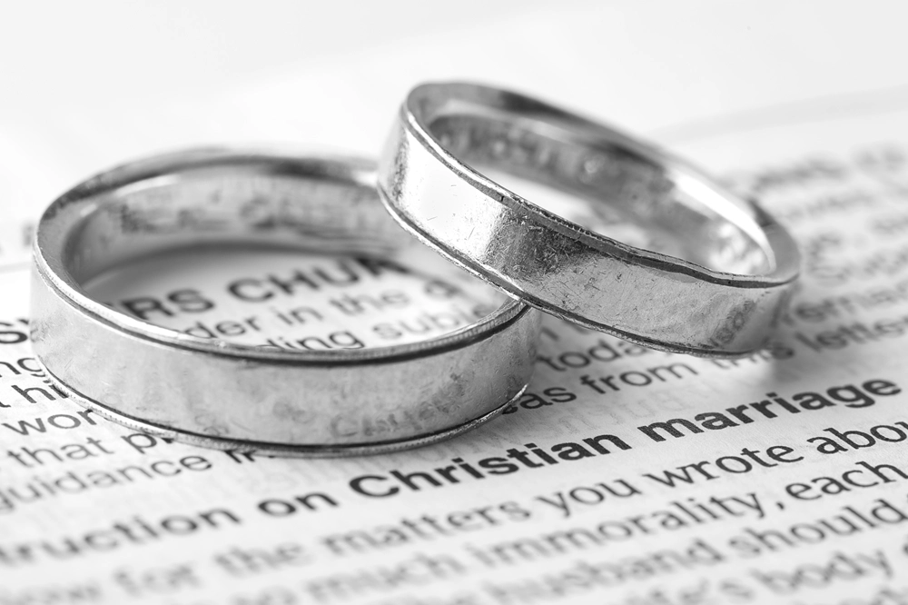 Two silver wedding rings resting on a page with the words “Christian marriage” in focus