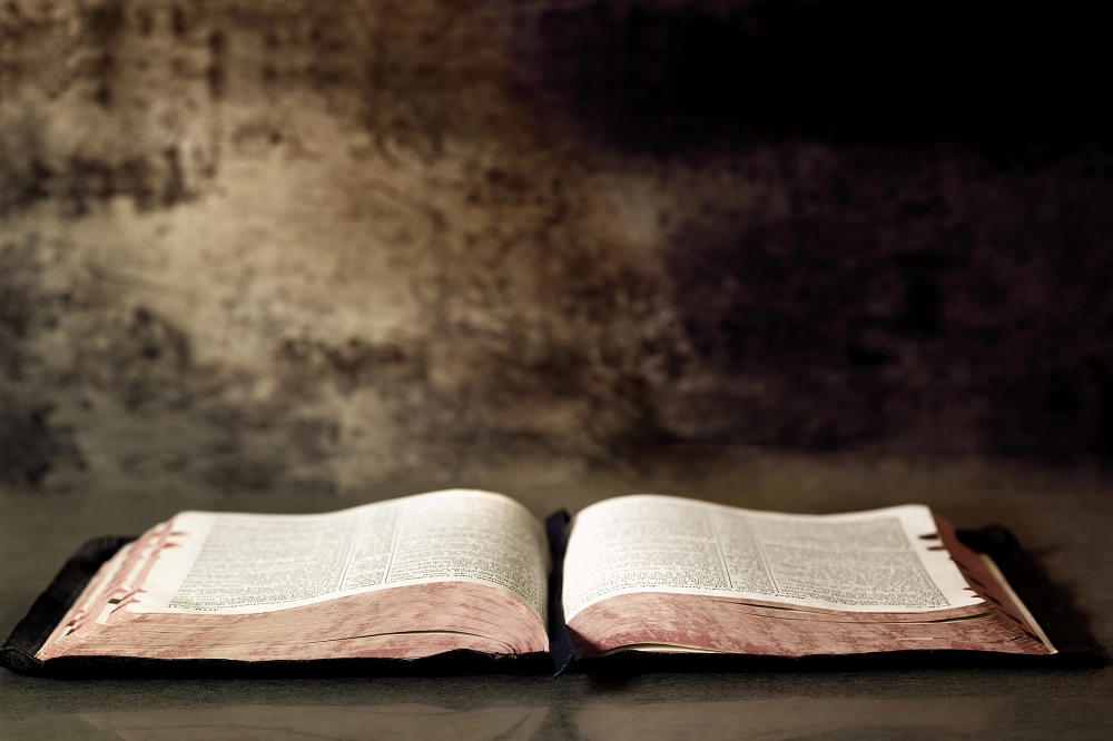 Open Bible on a dark rustic surface with soft lighting, symbolizing faith, wisdom, and reflection