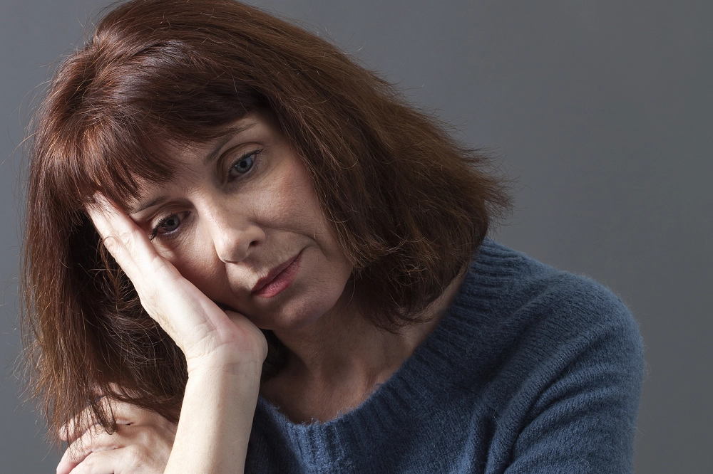 Woman resting her head on her hand with a sad expression, appearing tired or emotionally distressed