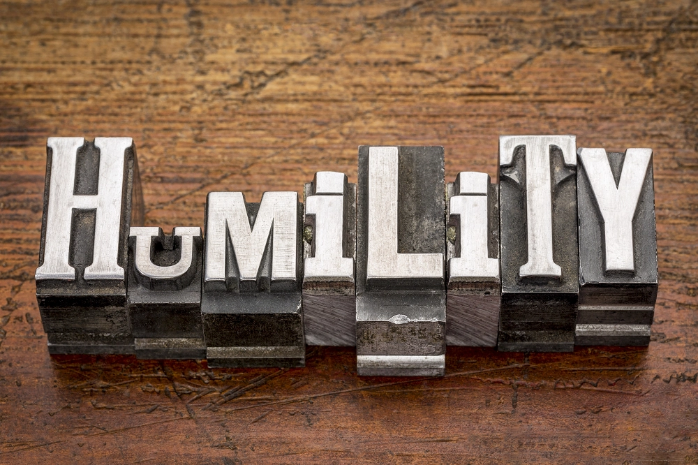 Metal letterpress blocks spelling the word “Humility” on a wooden surface