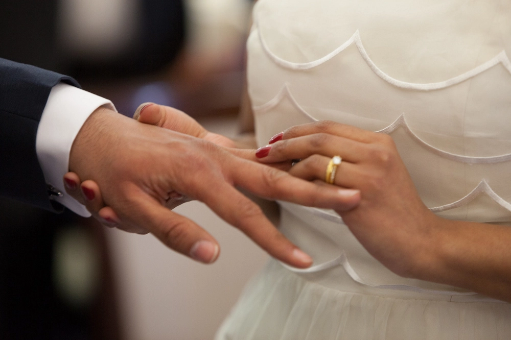 Bride placing a wedding ring on the groom’s finger during a marriage ceremony