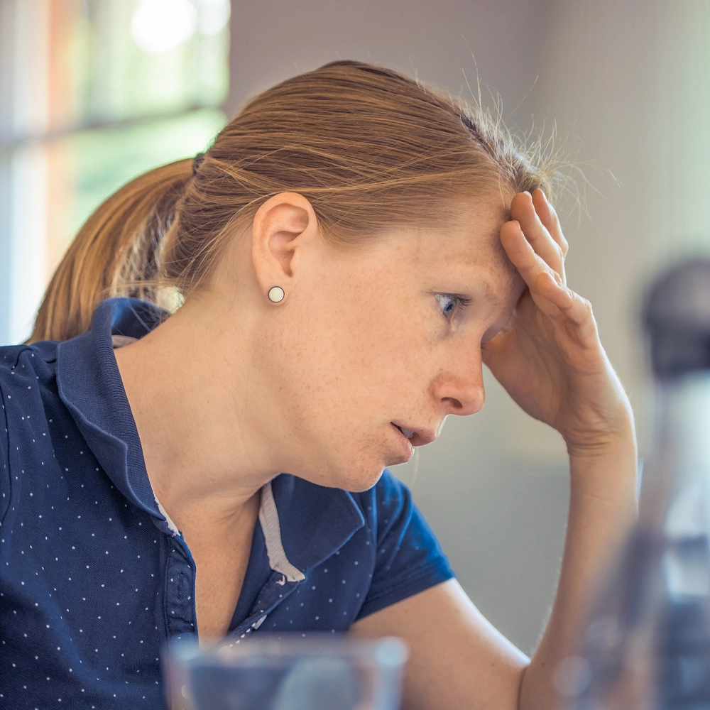 Woman resting her head on her hand, appearing stressed or worried while deep in thought