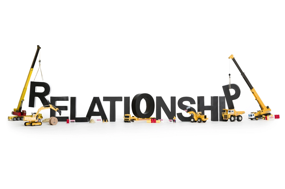 Construction cranes and trucks assembling the word “Relationship,” symbolizing effort and growth