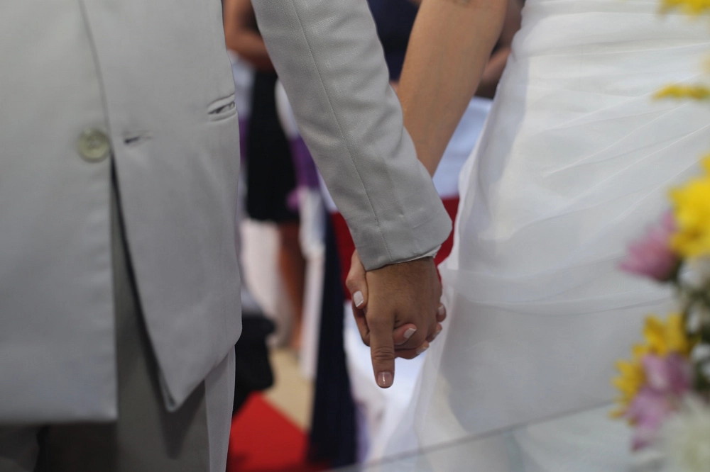 Close-up of a bride and groom holding hands during their wedding ceremony
