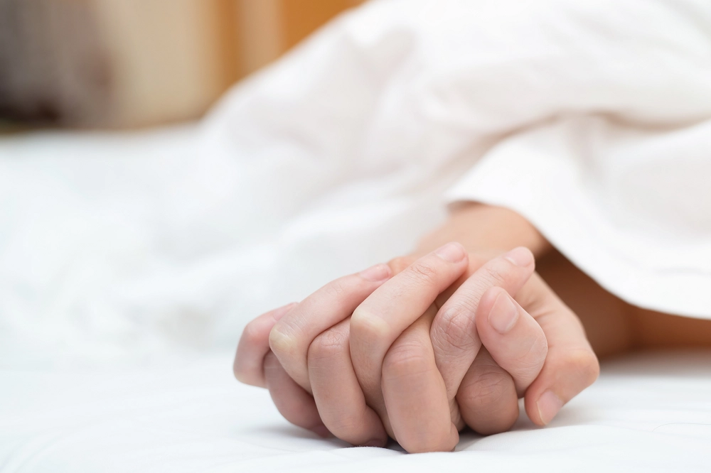 Close-up of couple holding hands in bed, symbolizing intimacy, trust, and emotional connection