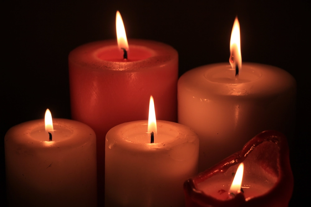 Four lit candles glowing softly in the dark, creating a warm and peaceful atmosphere