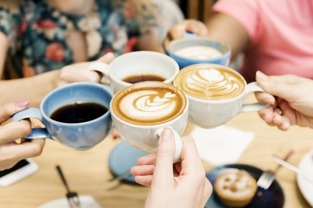Group of friends raising coffee cups together in a toast, showing connection, warmth, and shared moments