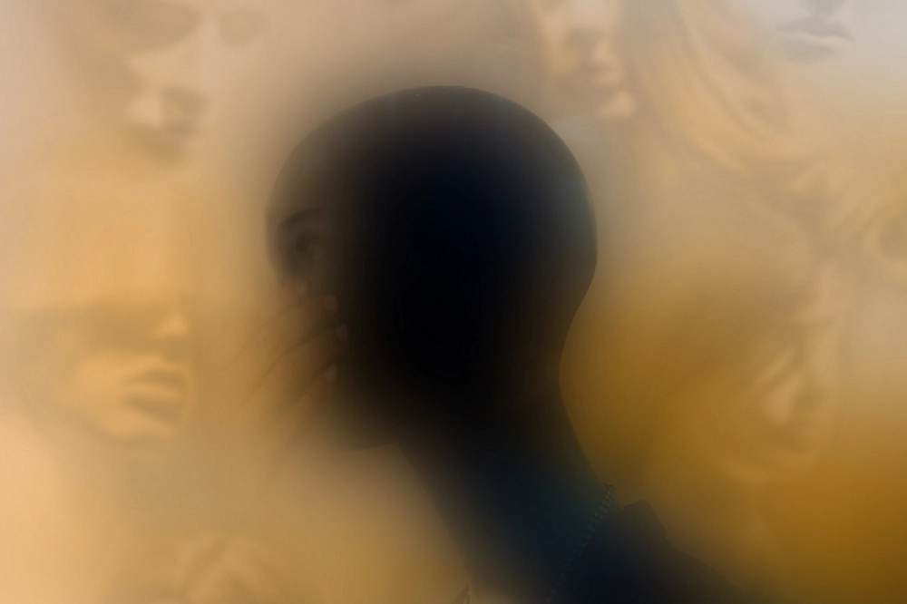 Blurred artistic image of a person surrounded by abstract faces, symbolizing confusion or mental distress