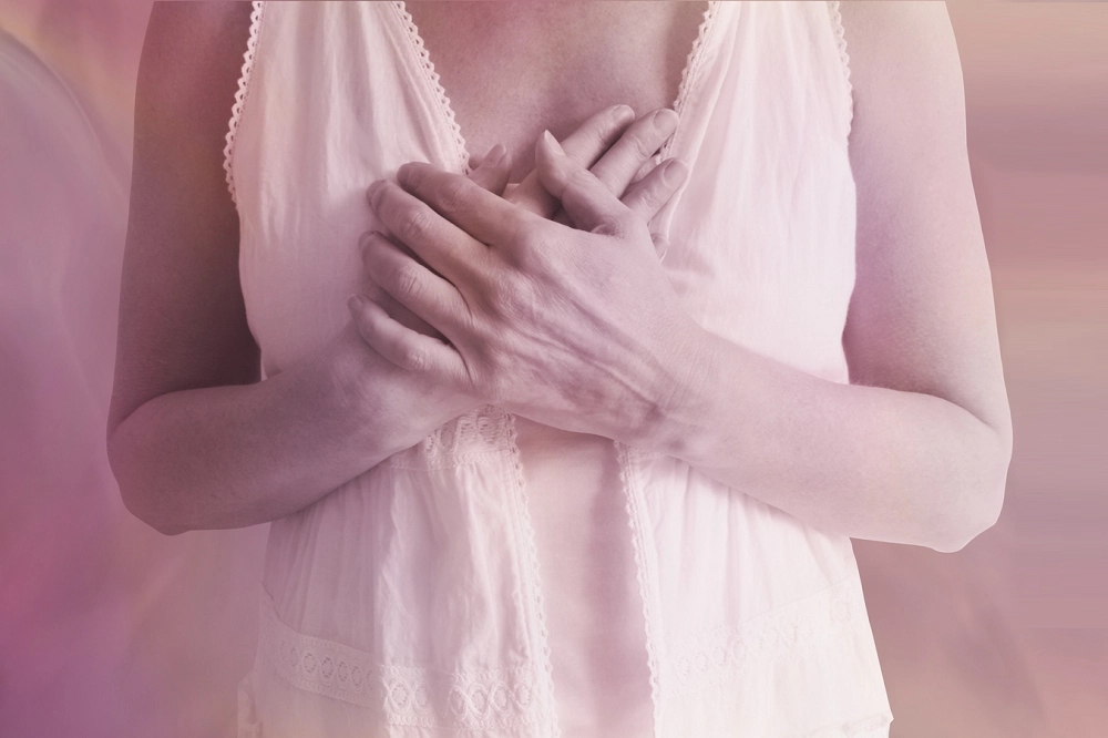 Woman holding her hands over her chest in a gesture of emotion or self-comfort
