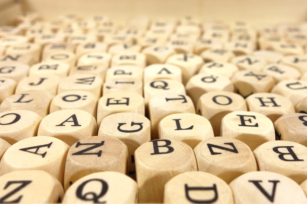Close-up of wooden letter blocks arranged randomly with black printed alphabets