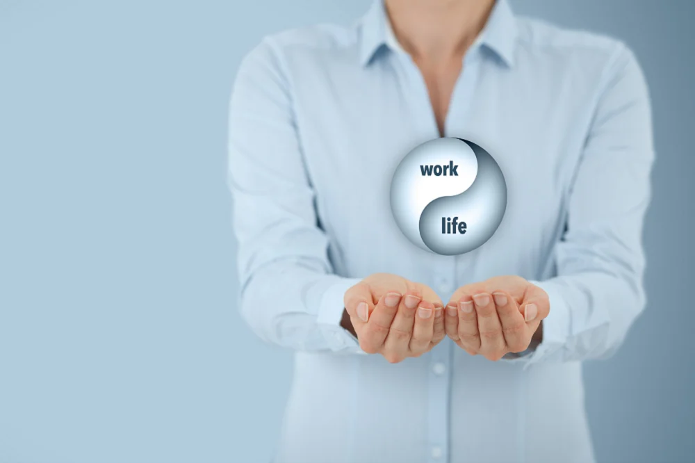 Person holding a yin-yang symbol with the words “work” and “life,” representing work-life balance